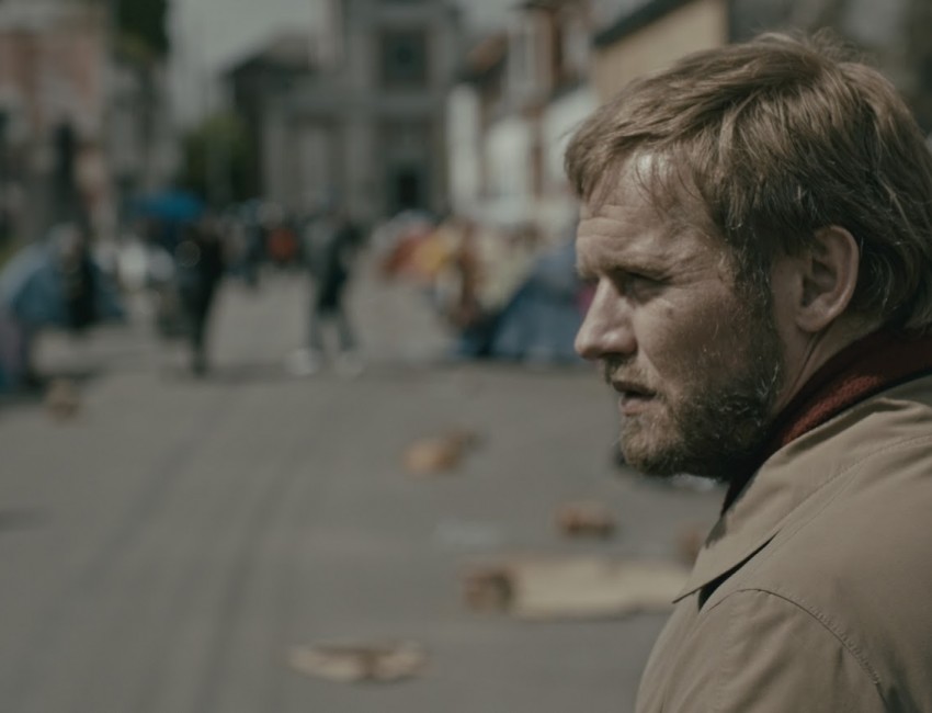 Un homme de profil est dans la rue et regarde devant lui