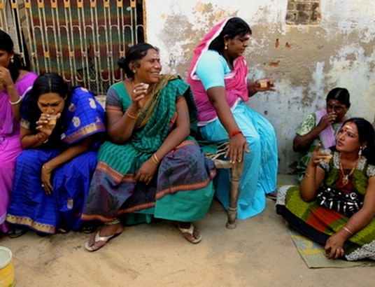 Des femmes indiennes sont habillées en tenue traditionnelle et sont assises devant une maison