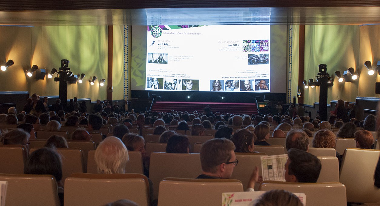 Une salle de cinéma comble, un écran projecteur 