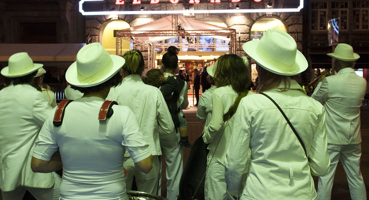 Un orchestre vêtu de blanc joue de la trompette en face du cinéma Eldorado.