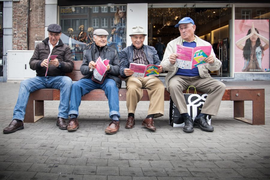 Quatre hommes assis sur un banc, ils tiennent le programme du FIFF.