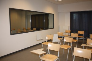 Salle avec banc scolaire et une vitre sans tain.