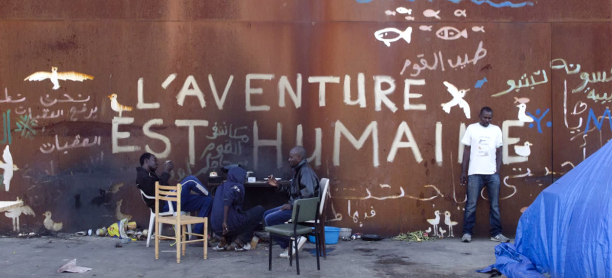 Réfugiés à Calais devant un slogan "L'aventure est humaine"