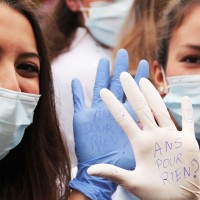 Deux étudiantes montrent des inscriptions sur leurs mains : "5ans pour rien!".