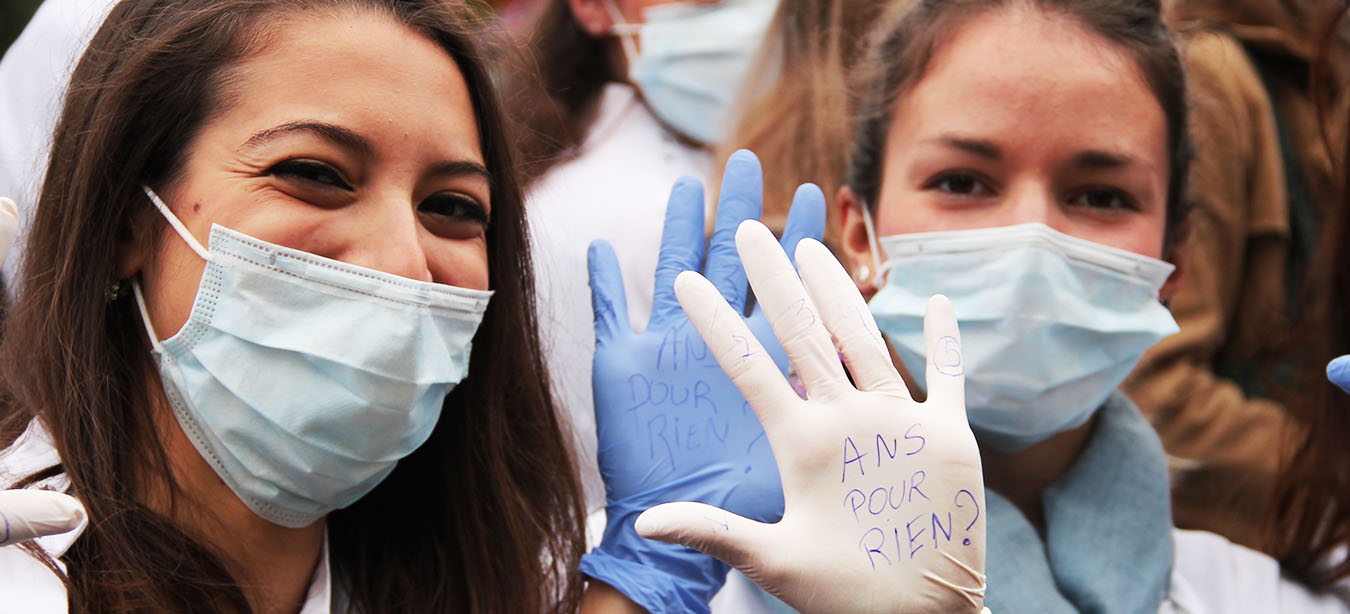 Deux étudiantes montrent des inscriptions sur leurs mains : "5ans pour rien!".