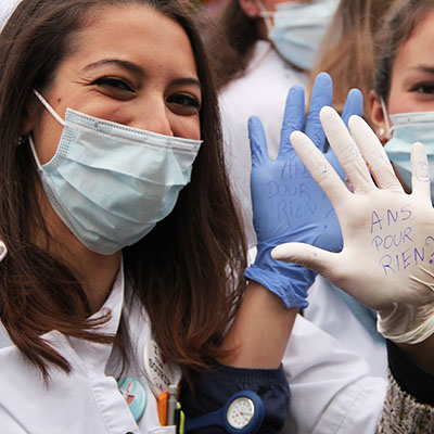 Deux étudiantes montrent des inscriptions sur leurs mains : "5ans pour rien!".