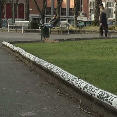 Une phrase est rédigée avec de la peinture sur le sol dans un parc.