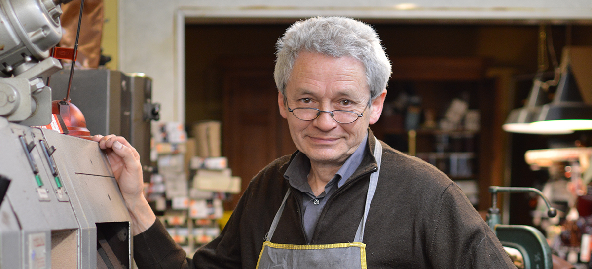 Eric, cordonnier, se trouve dans son atelier où il travaille sur une paire de chaussures