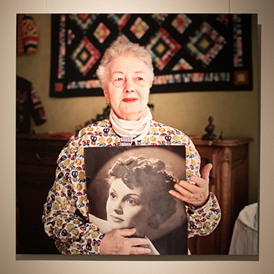 Photo exposée dans un musée sur laquelle une femme tient un portrait.