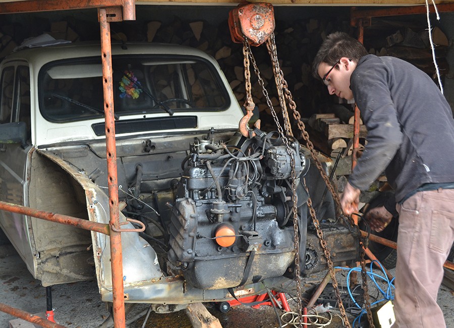 Un homme inspecte le moteur d'une Renault 4L