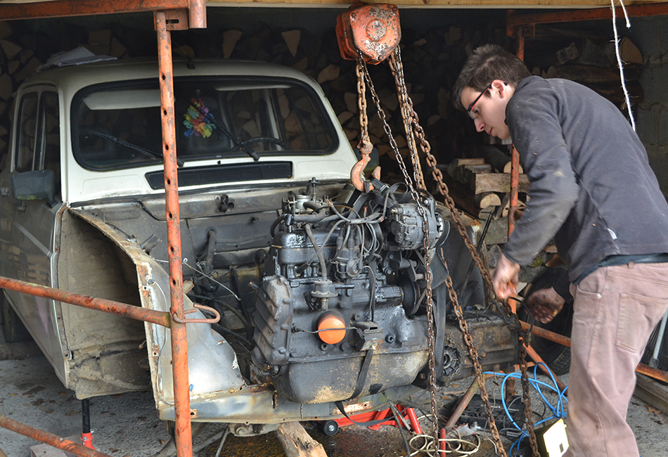 Un homme inspecte le moteur d'une Renault 4L