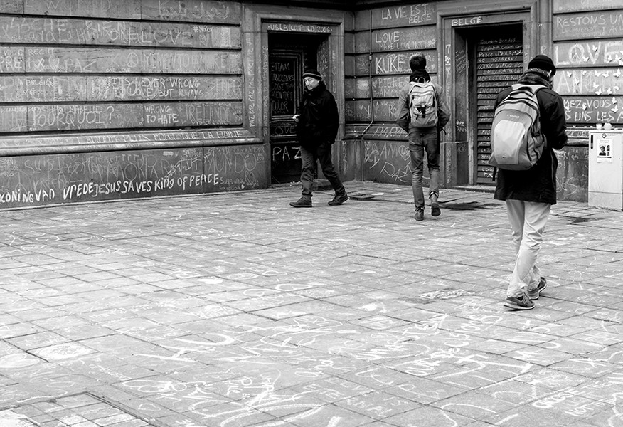 Des gens marchent et regardent les murs de la Place de la Bourse.