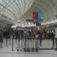 hall d'aéroport rempli de gens. Des charrettes sont à l'avant-plan.