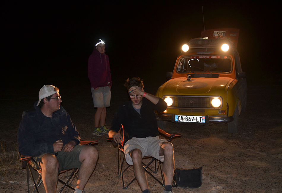 sous la lumière des phares des voitures, les conducteurs sont assis dans des chaises de camping.