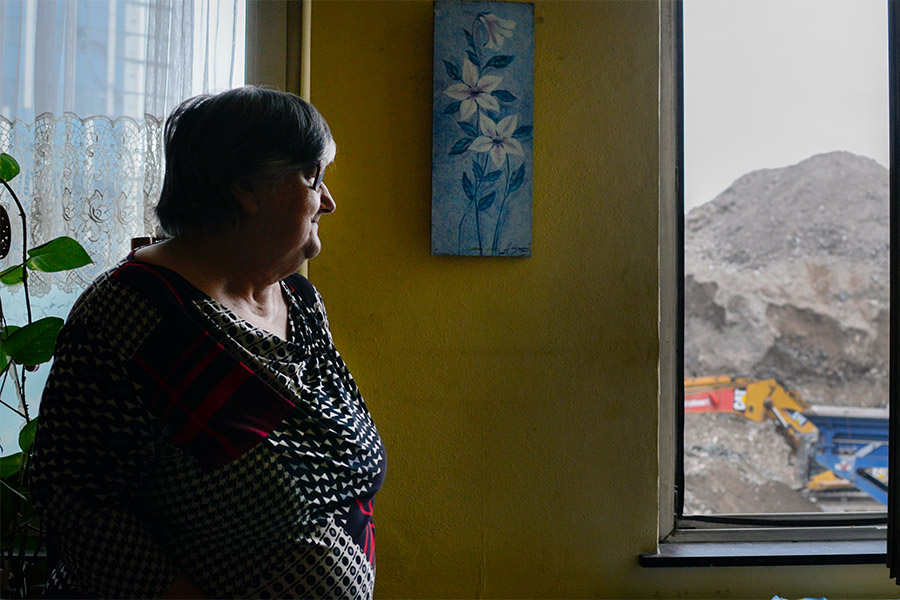 Solange, pensionnée belge, regarde par la fenêtre de son salon.