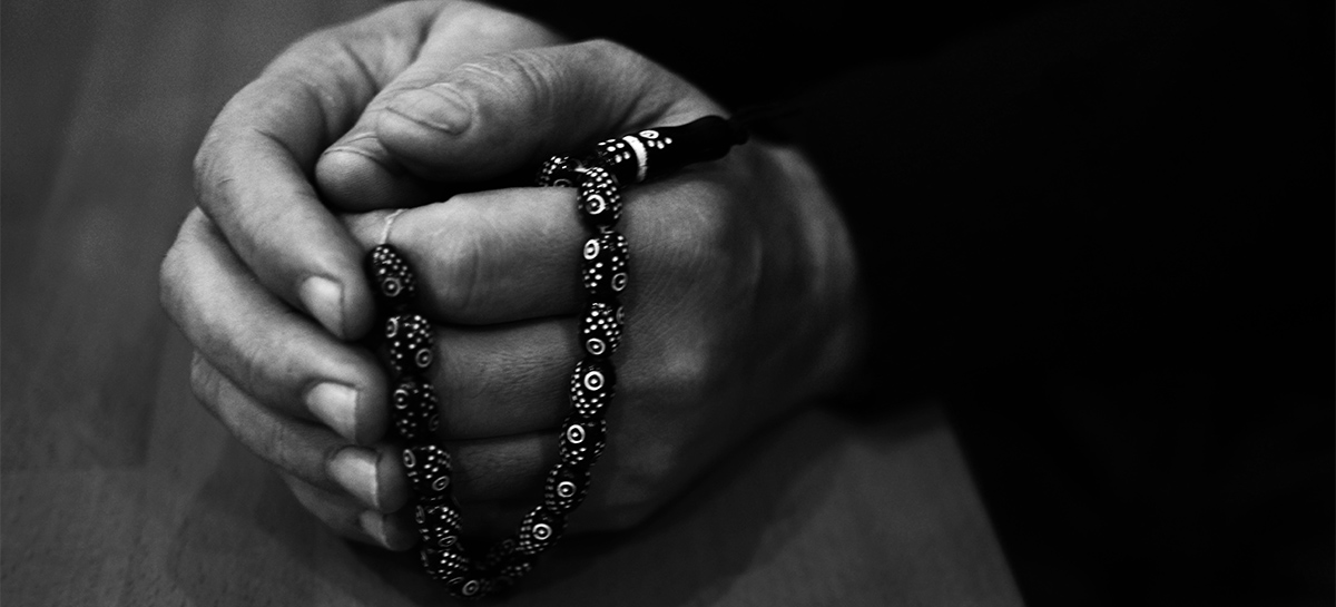 Musa, ancien détenu, tient un collier de perles dans ses mains.