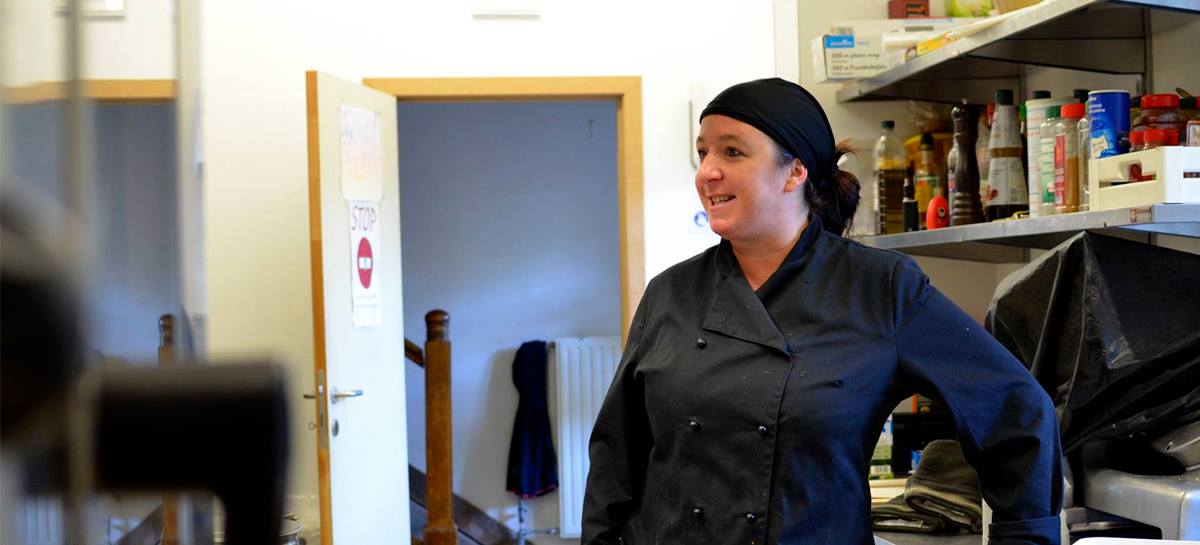 Marie, en uniforme, adossée à son plan de travail