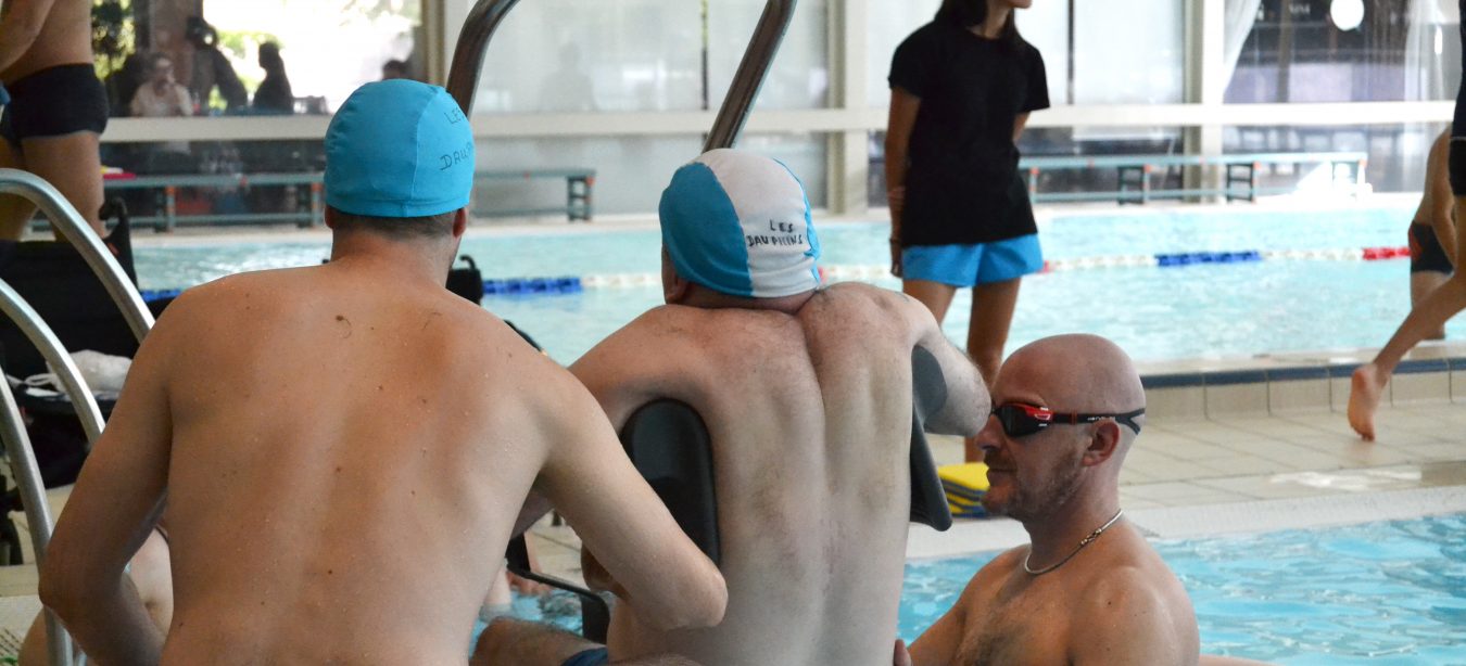 Un membre du club des dauphins rejoint ses camarades dans l'eau grâce à un lift spécialement conçu pour cela.