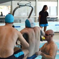 Un membre du club des dauphins rejoint ses camarades dans l'eau grâce à un lift spécialement conçu pour cela.