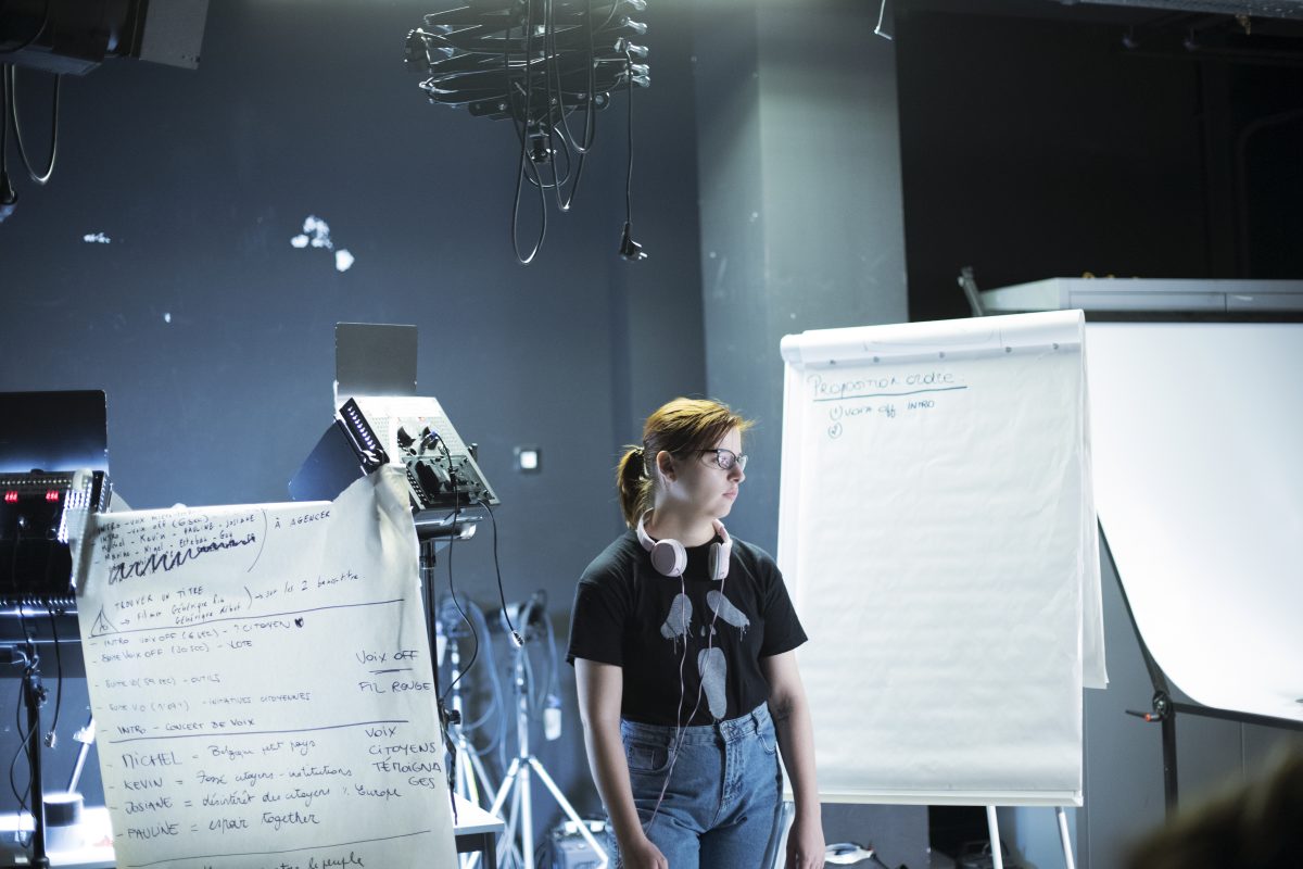 Une élève au studio entre deux panneaux remplis d'idées