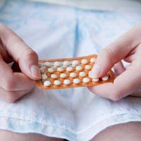 Des mains de femme tiennent une plaquette de pilule contraceptive.