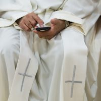 Un prêtre consulte un téléphone portable
