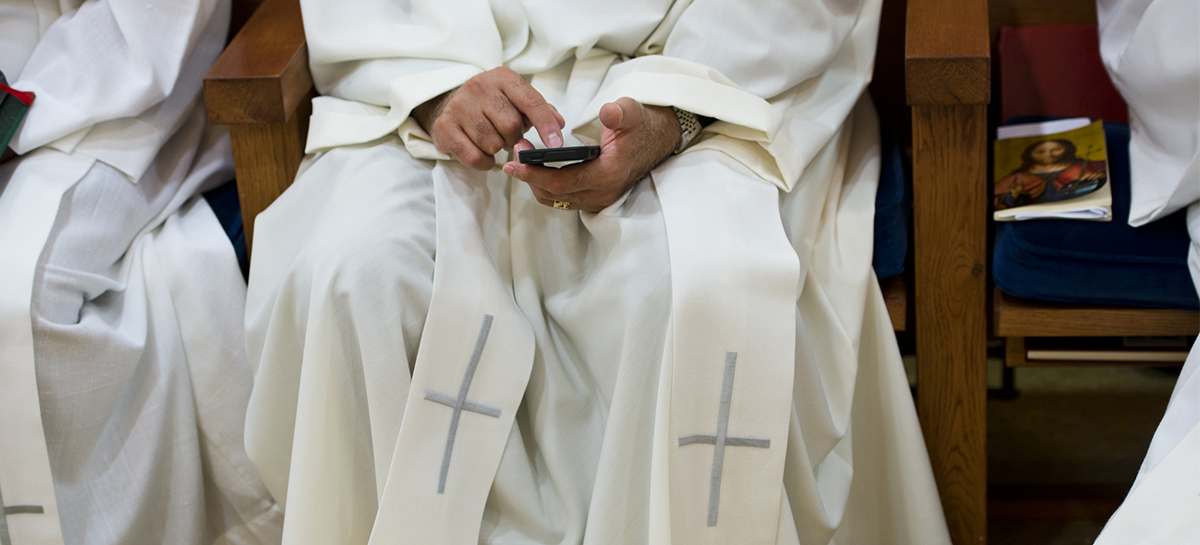 Un prêtre consulte un téléphone portable