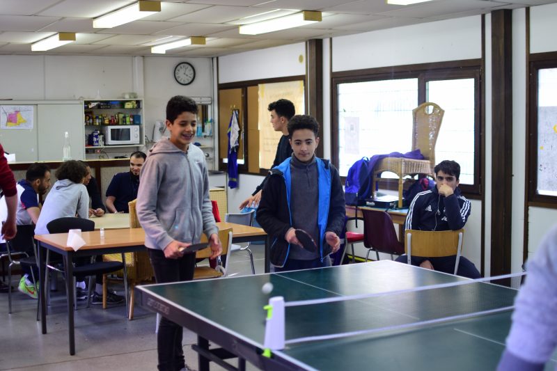 Deux enfants jouent au ping-pong.