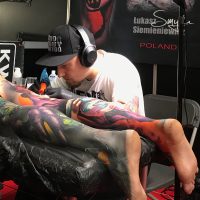 Un artiste tatoueur est en plein travail avec un client.