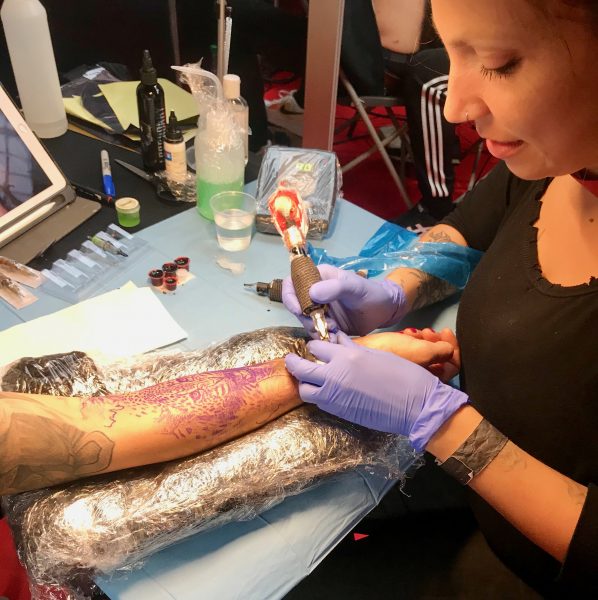 Une artiste de tatouages est occupée avec une cliente