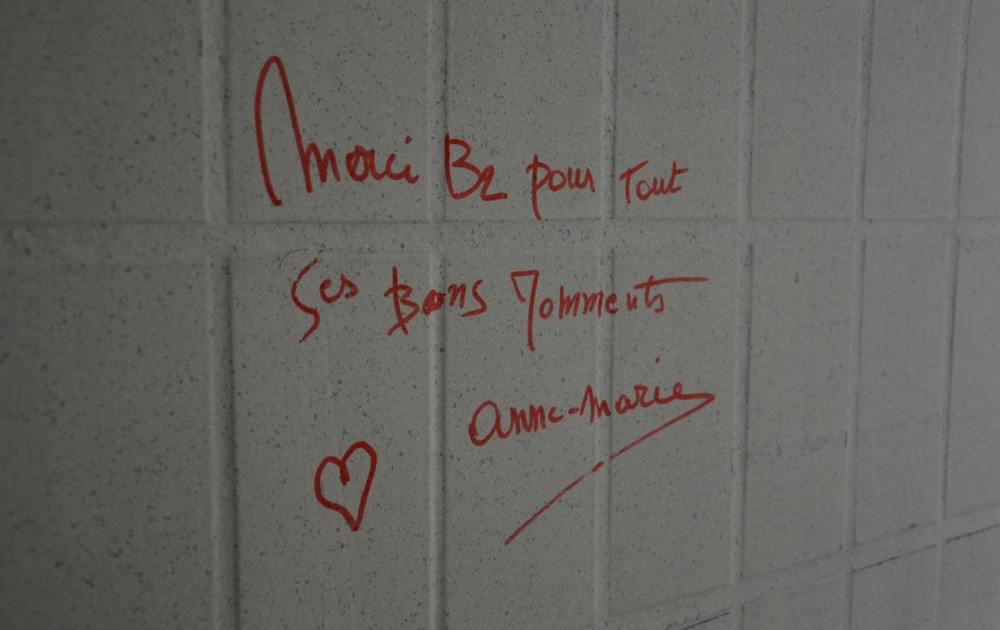 Mot de remerciement écrit au feutre rouge sur un mur carrelé.