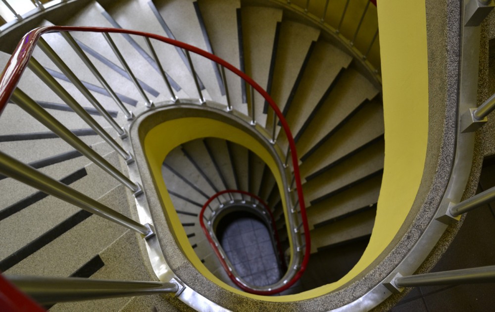 Escaliers en colimaçon avec rampe rouge.