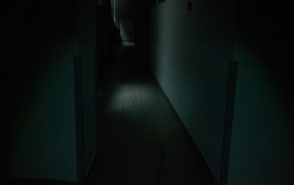 Couloir étroit et obscur avec traînée au sol.