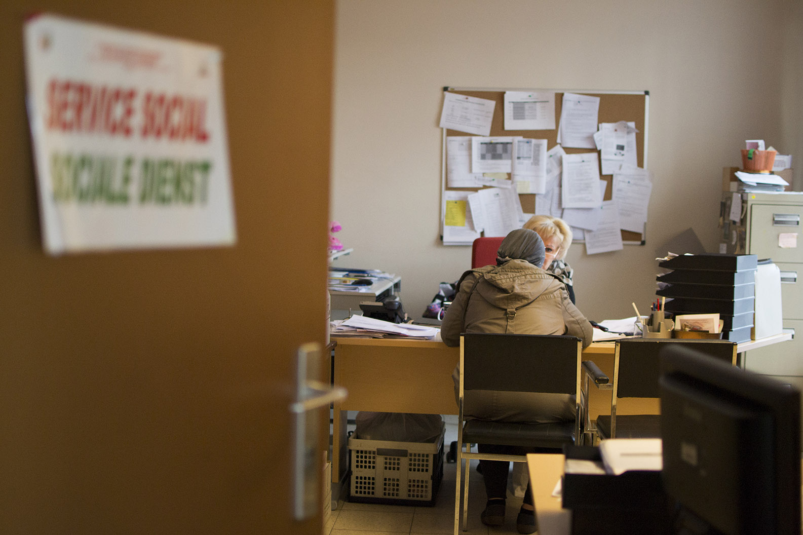 Au fond de la pièce, deux dames sont installées à un bureau. Une est assistance sociale, l’autre est venue demander des conseils.